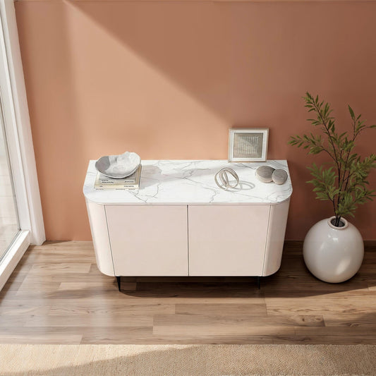 Modern sideboard with marble countertop and decorative items against a peach wall.