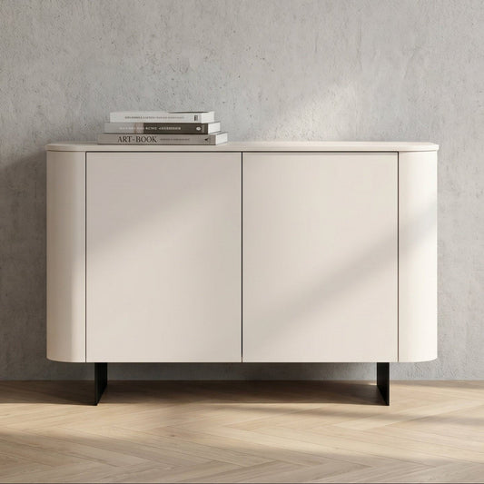 A modern sideboard cabinet with two doors, featuring a curved outer frame, a light beige finish, and black legs, set against a textured gray wall and light wood herringbone floor.