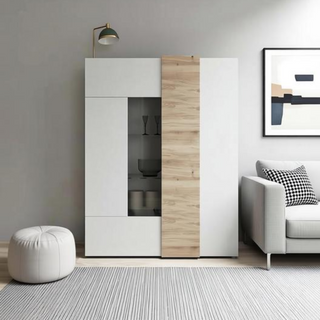 A modern white and light wood sliding display cabinet in a minimalist living room setting next to a light gray sofa and a white pouf.