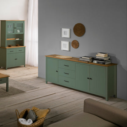 A sage green wooden sideboard cabinet with three drawers and two cabinet doors, styled in a modern living room setting against a gray wall.