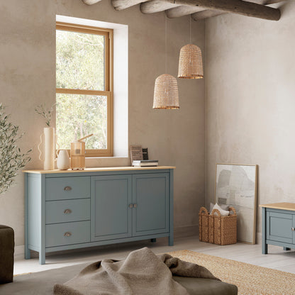 A styled interior room showing a light blue painted wooden cabinet with a light wood top, a matching TV stand, and a wall-mounted television in a rustic living room setting.