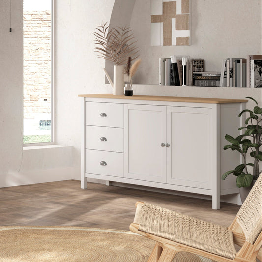 A styled living room featuring a white wooden TV stand with a light wood top, a matching white sideboard cabinet, and a woven rattan pendant light hanging above.