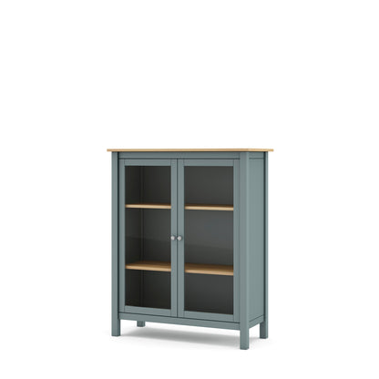 A small two-door cabinet with a muted blue-gray painted frame, light natural wood top and shelves, and dark glass doors, shown on a plain white background.