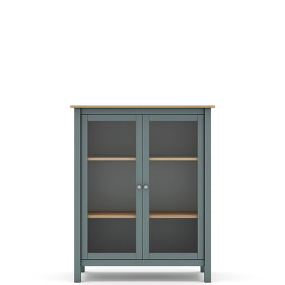 A tall two-door cabinet with a muted blue-gray painted frame, light natural wood top and shelves, and dark glass doors, shown on a plain white background.