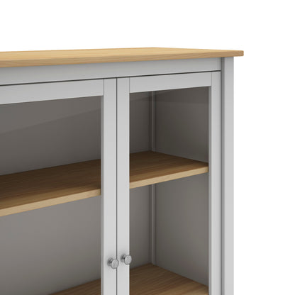 A close-up of a white storage cabinet with light wood grain shelves and a matching wood top, featuring two glass-front doors with silver knobs.