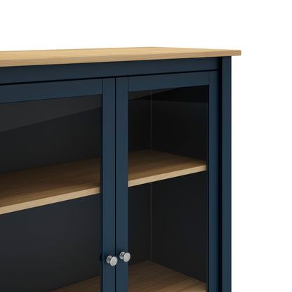 Close-up of a navy blue cabinet with glass doors, light wood shelves, and a light wood top, shown against a white background.