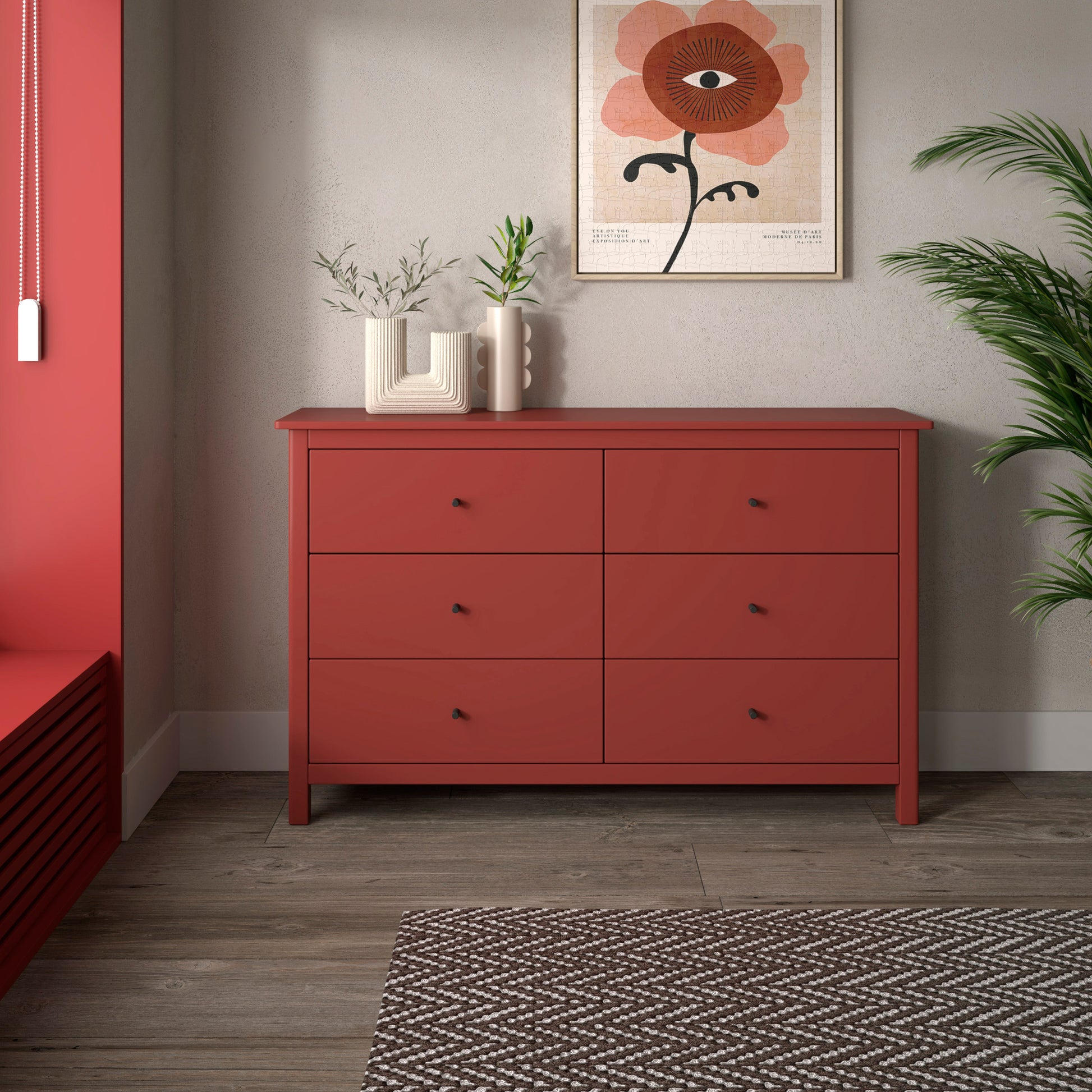 Red dresser against a gray wall with a floral painting and plants.