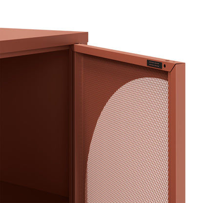 Close-up of a modern storage cabinet or shelf with a terracotta rust finish, featuring a perforated metal front panel and a small black control or label plate near the top edge.