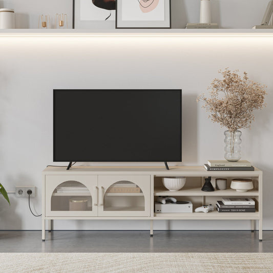 A modern light beige TV stand console with open shelves and arched cabinet doors, styled in a living room setting with a black flat-screen TV, decorative books, a vase of dried flowers, and wall shelves above.