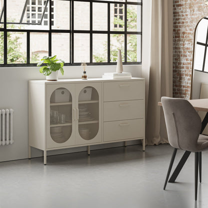 A cream-colored sideboard cabinet in a modern dining room setting, featuring two glass-front doors on the left and three drawers on the right, styled with a small plant and decorative items on top.