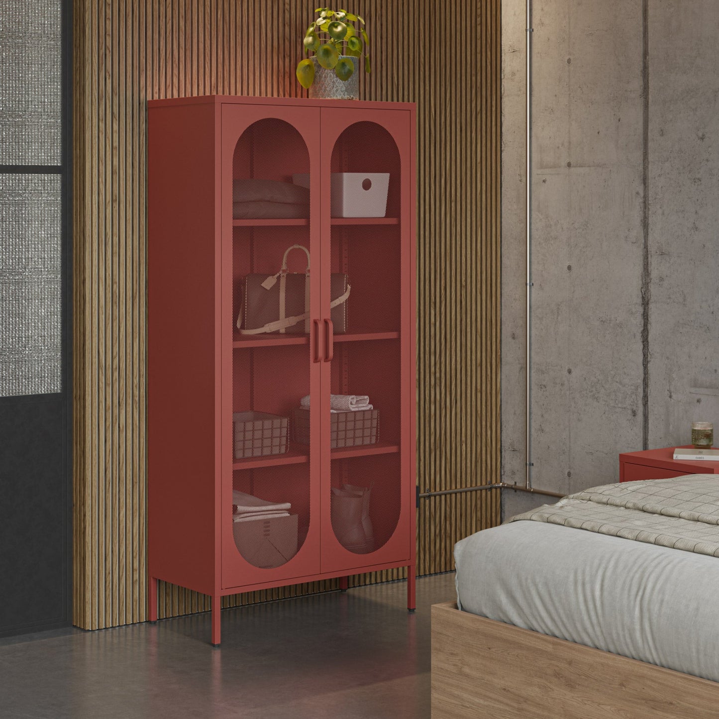 A tall coral-red two-door storage cabinet with arched glass panels stands in a bedroom setting against a slatted wood wall, with a bed and concrete wall visible.
