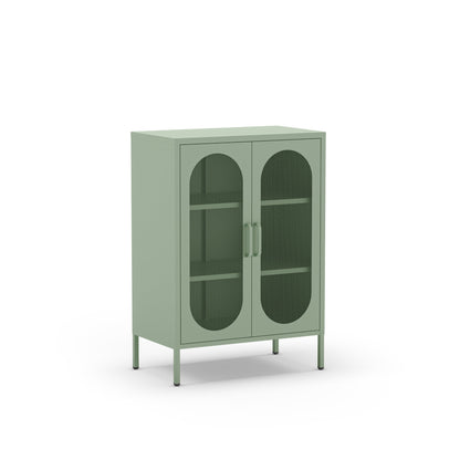 A sage green metal cabinet with two arched glass doors, two interior shelves, and slim metal legs, shown on a plain white background.