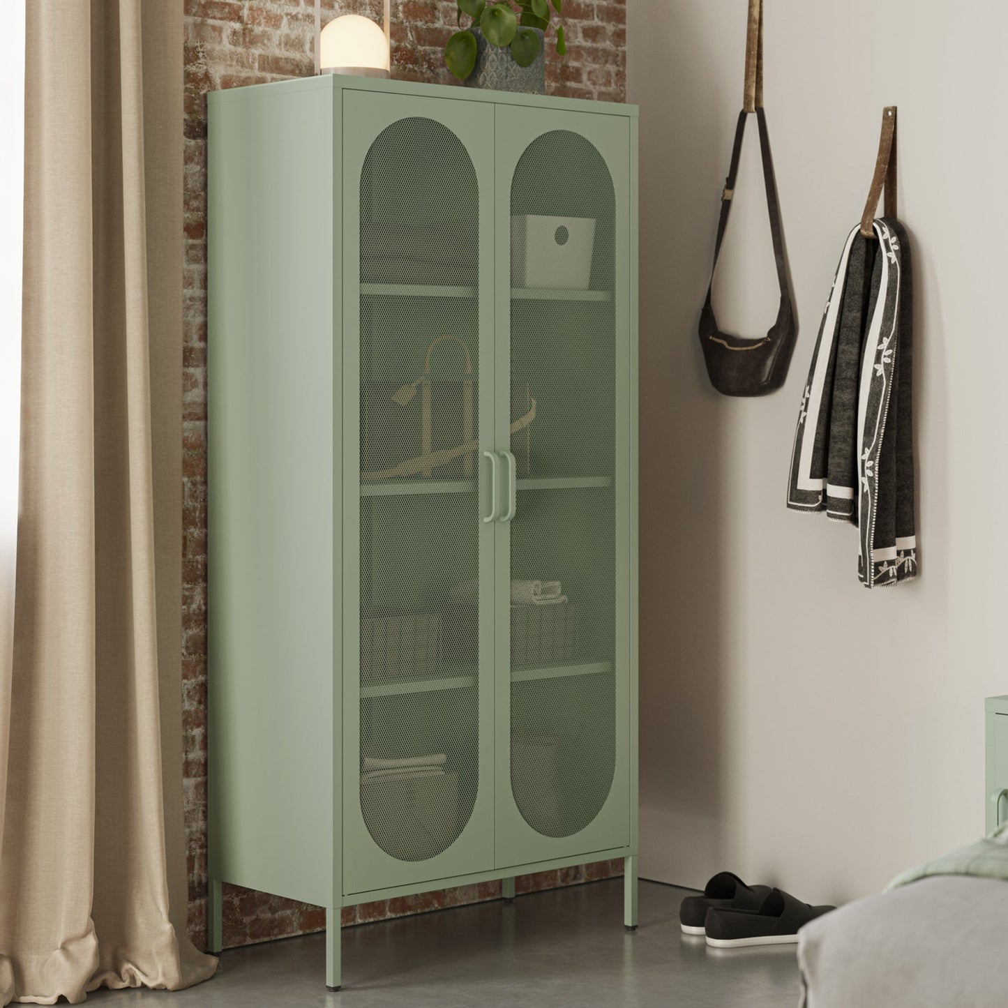 Green glass-fronted cabinet in a room with a brick wall and bed.
