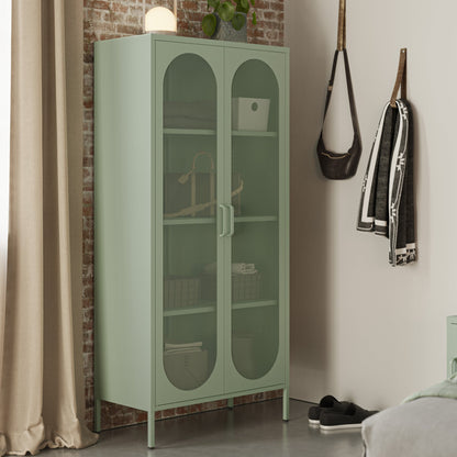 Green glass-fronted cabinet in a room with a brick wall and bed.
