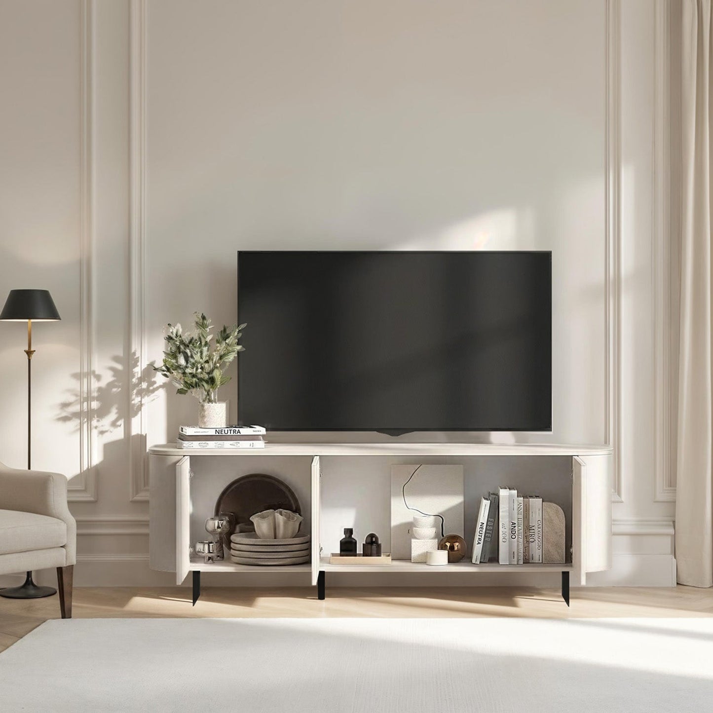 Modern living room with a television on a white stand, light-colored walls, and a window with curtains.