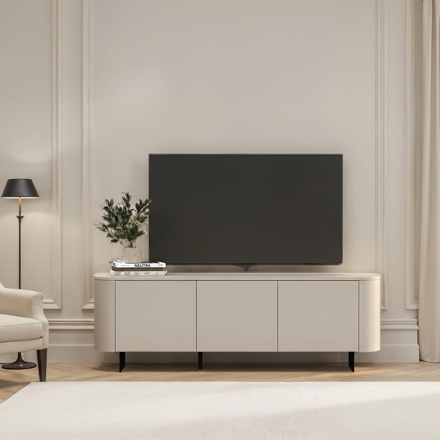 Modern living room with a television on a white cabinet, light-colored walls, and a window with curtains.