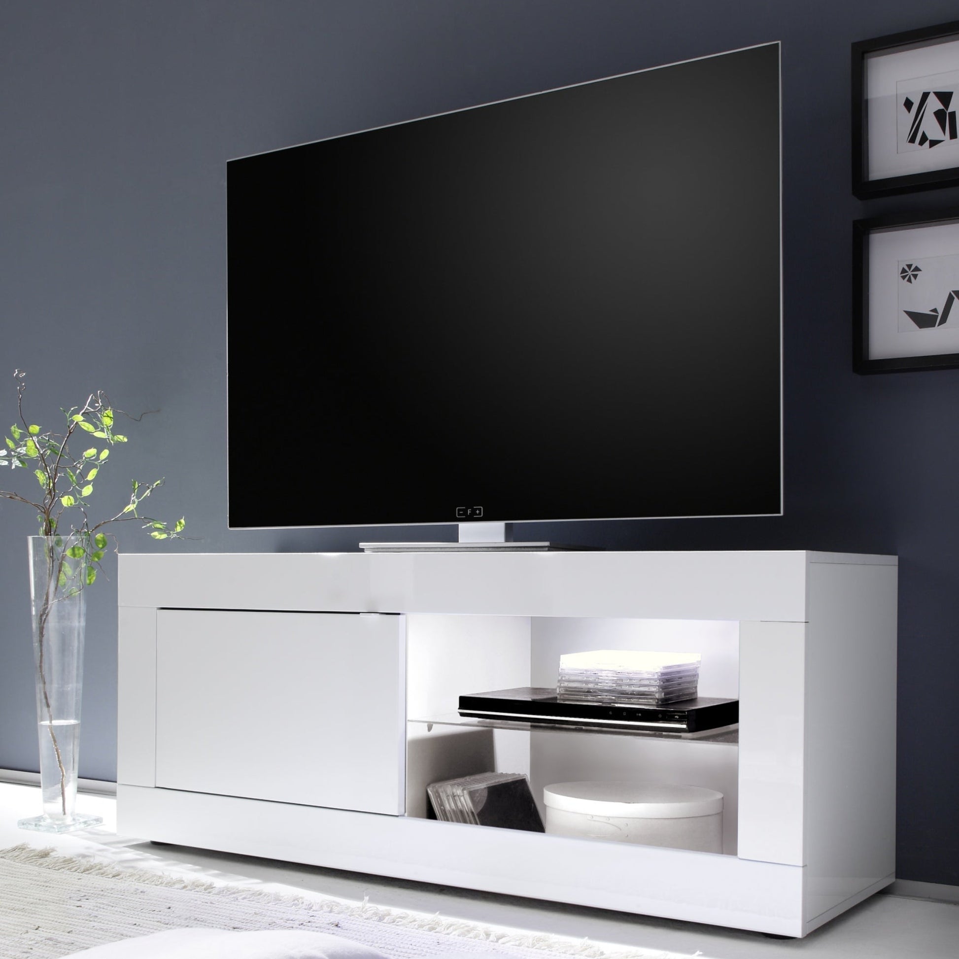 Modern white TV stand with a flat-screen TV against a dark wall.