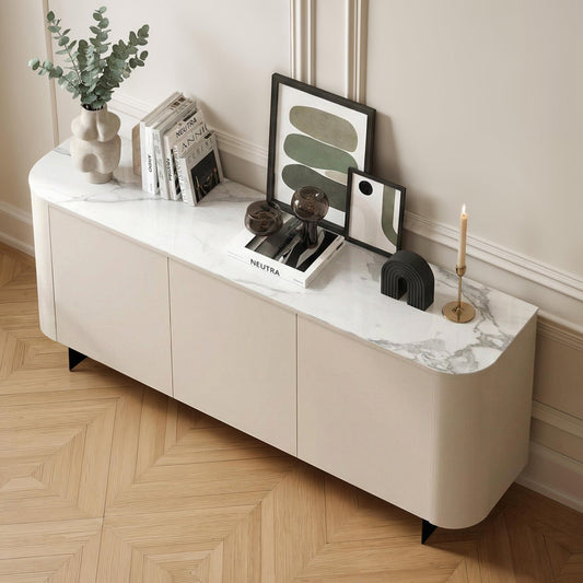 White sideboard with decorative items against a wall with wainscoting.