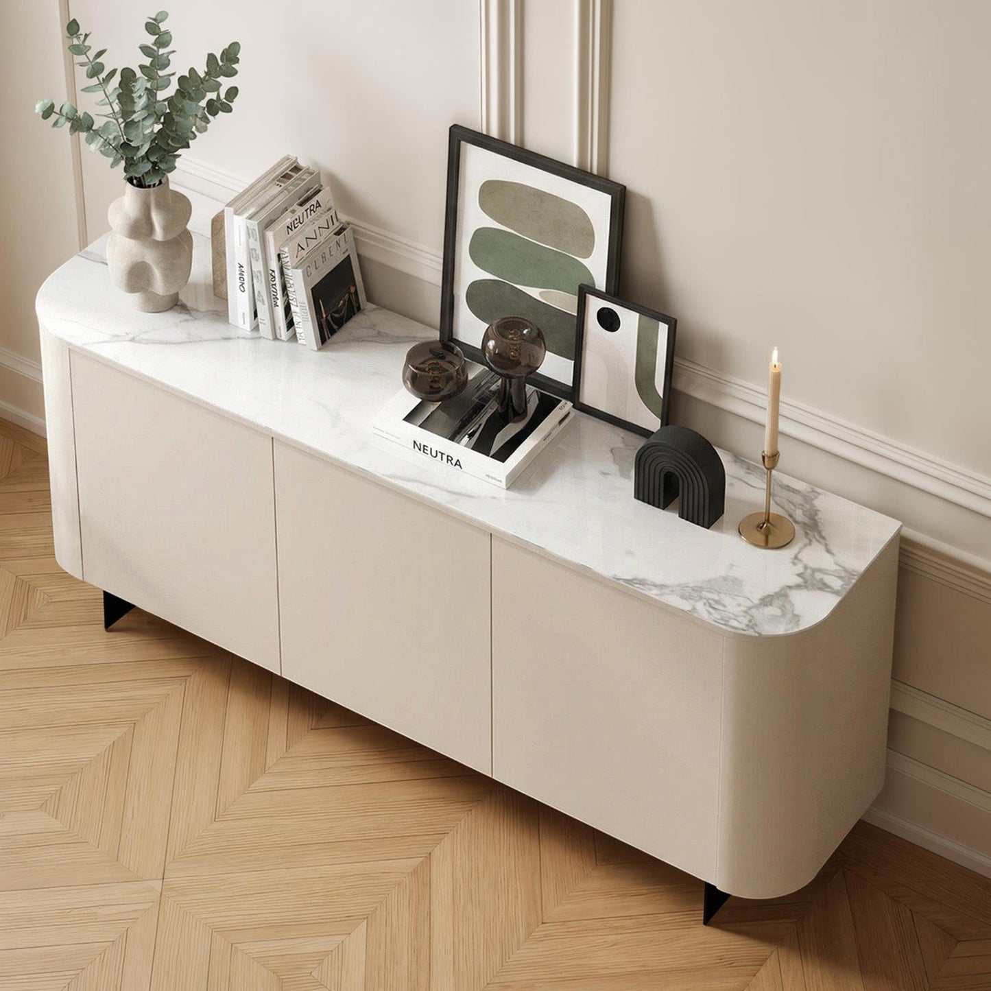 White sideboard with decorative items against a wall with wainscoting.
