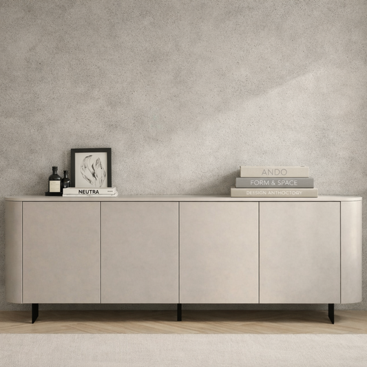 A modern sideboard cabinet with a light beige wood-grain finish and black legs, styled in a minimalist room with a textured gray wall, wooden floor, and white curtains.