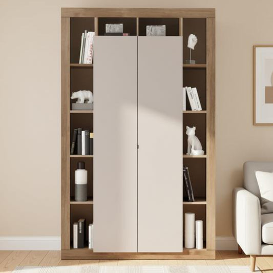 A tall built-in wardrobe or bookcase with two large light beige doors in the center and open shelving on both sides, shown in a styled room with books, decor, a rug, and part of a sofa.